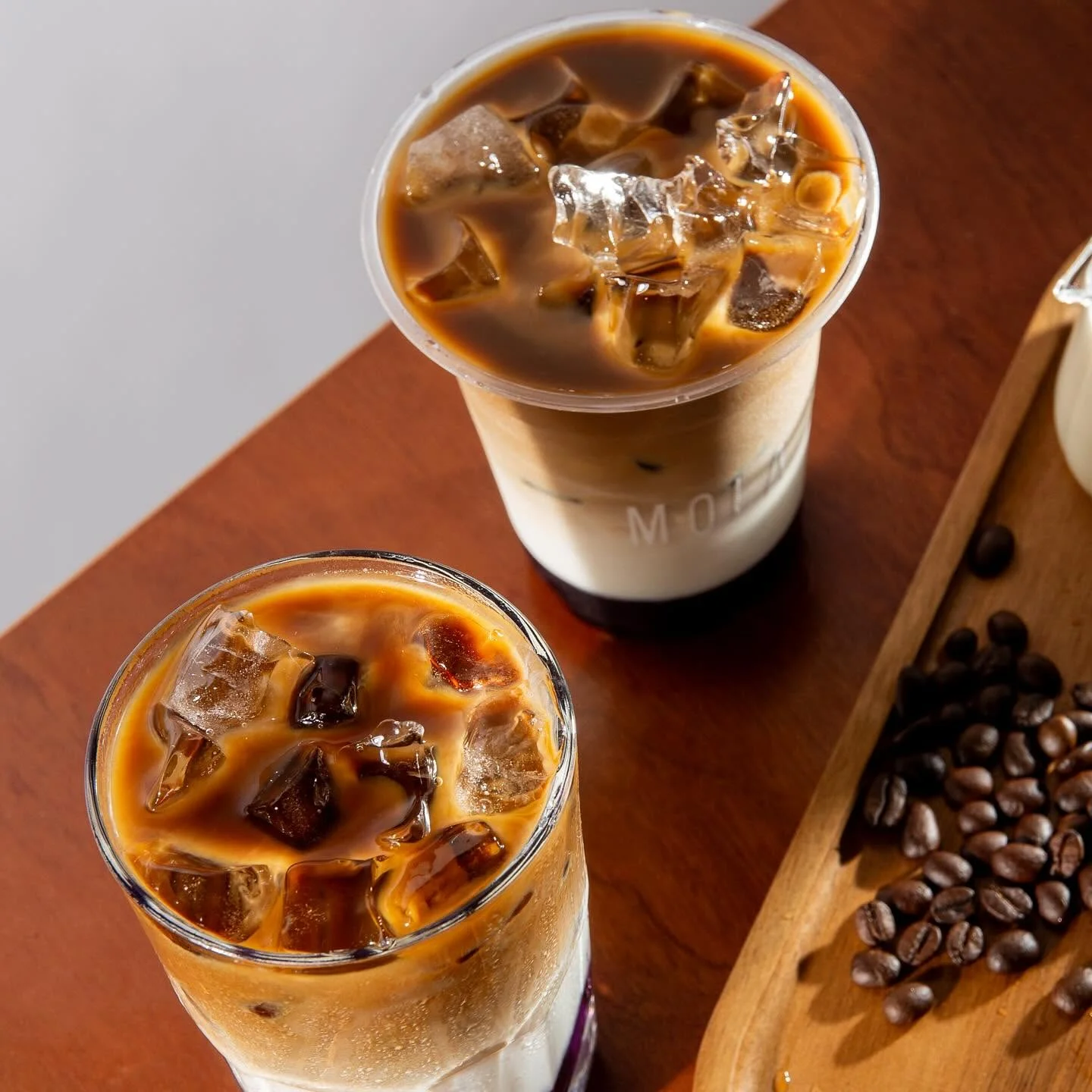 Dos lattes fríos con hielo sobre una mesa de madera